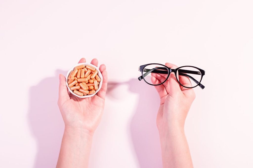 holding-eyeglasses-in-one-hand-and-vitamins-in-other