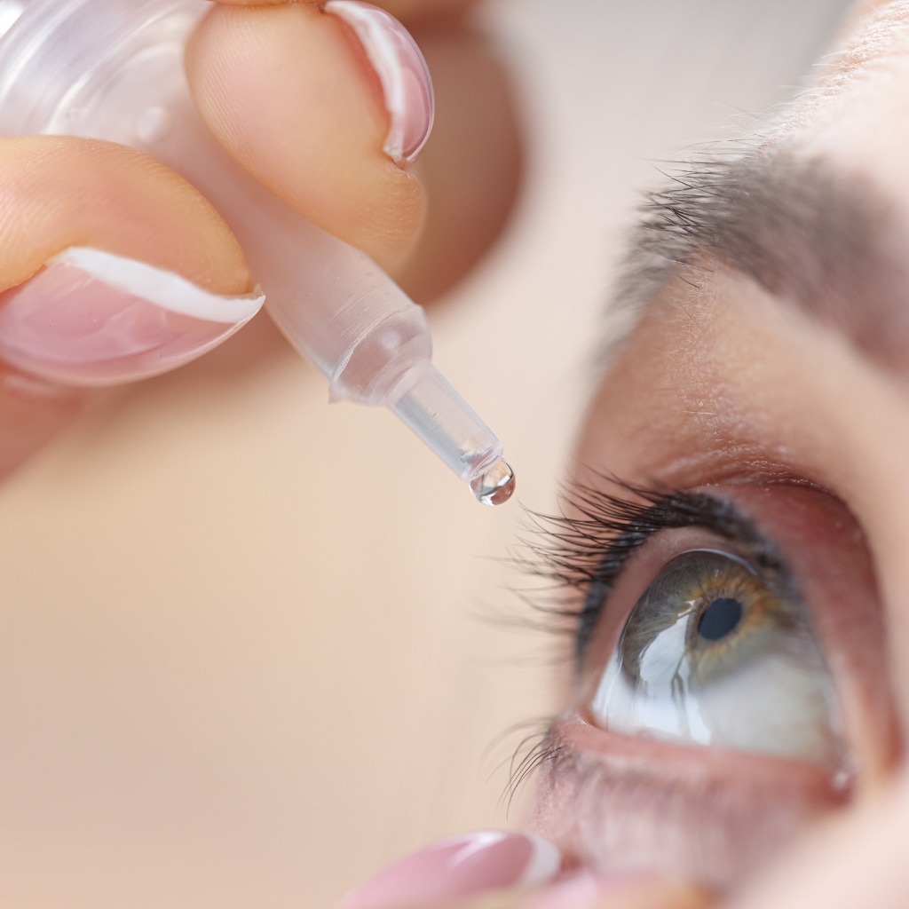 Woman drips eye drops into her eyes